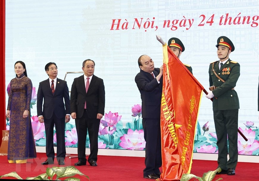 Chủ tịch nước Nguyễn Xuân Phúc gắn Huân chương Lao động hạng Nhất lên lá cờ truyền thống của Văn phòng Chủ tịch nước.