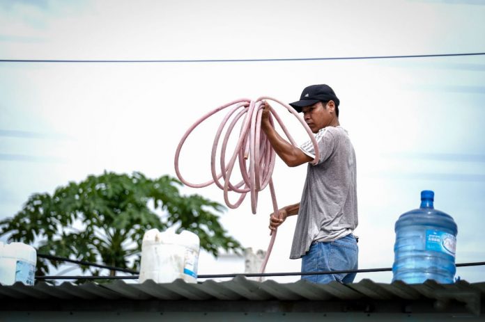 Người dân cột các thùng nước trên mái nhà để phòng tránh bão Người dân cột các thùng nước trên mái nhà để phòng tránh bão
