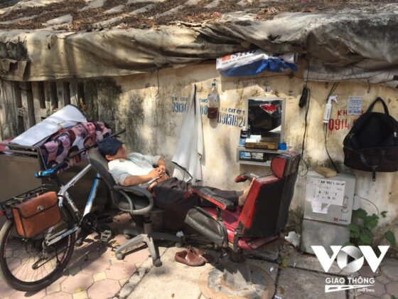 Một người thợ cắt t&oacute;c tr&ecirc;n vỉa h&egrave; phố Nguyễn Du nằm nghỉ khi vắng kh&aacute;ch