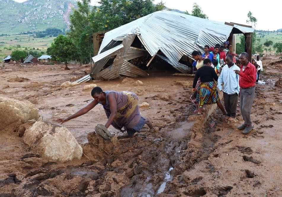 Dân làng Mtauchira đi ngang qua một ngôi nhà bị hư hại do lở đất sau cơn bão Freddy ở Blantyre, Malawi, ngày 16/3. 