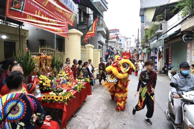 Người d&acirc;n l&agrave;ng b&agrave;y b&agrave;n lễ ra trước cửa, tr&ecirc;n đường đo&agrave;n rước đi qua.