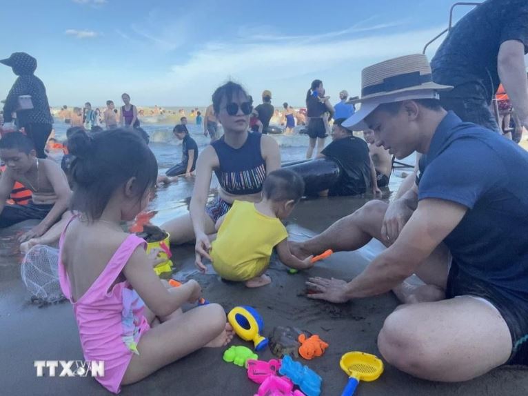 Du khách thích thú chơi đùa trên bãi biển Sầm Sơn.