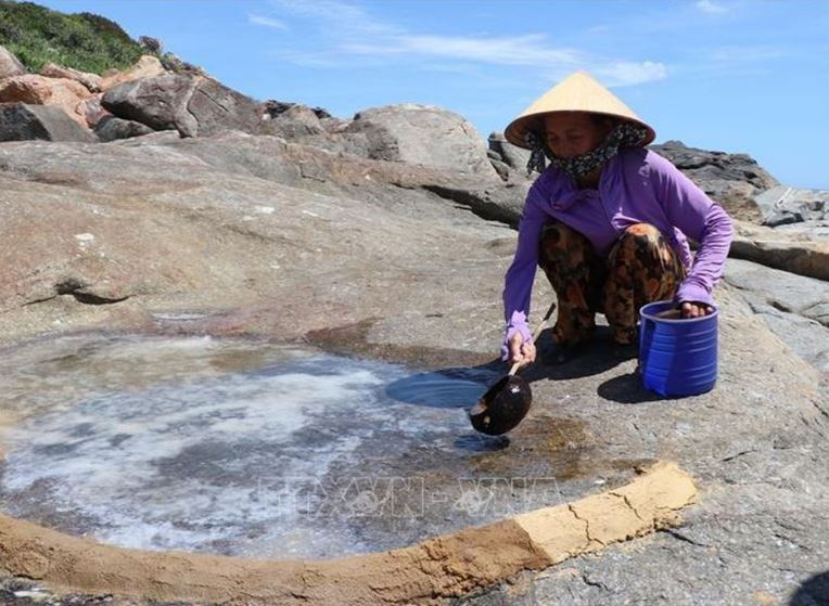 Người dân xóm Cỏ chêm nước biển vào các ô đá kết tinh muối đã được be bờ bằng đất sét để tăng độ dày cho muối.