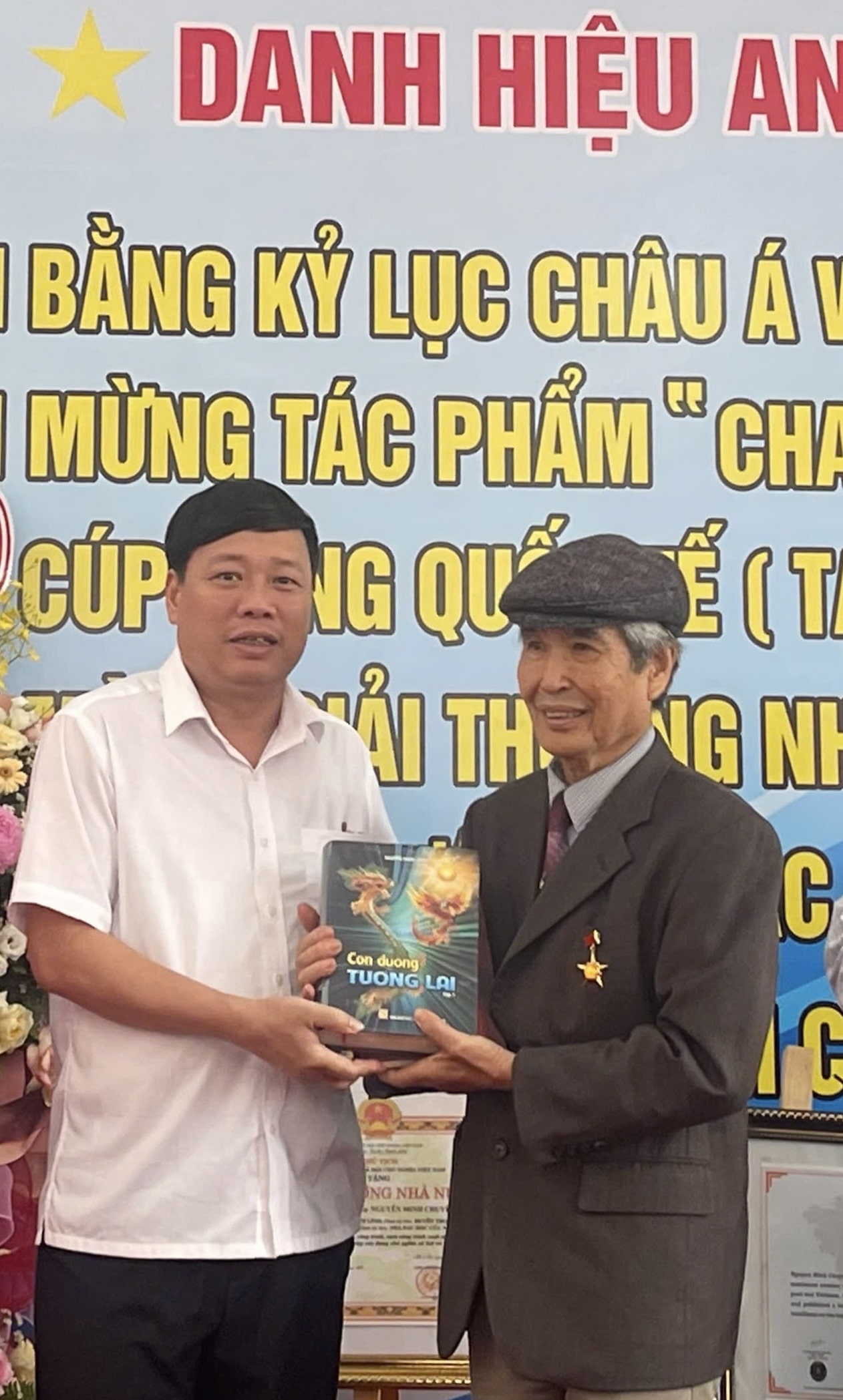 Nhà văn Phùng Văn Khai (bìa trái) tặng sách "Con đường tương lai" của nhà văn, nhà nghiên cứu Nguyễn Xuân Tuấn cho Anh hùng Lao động, nhà văn, nhà báo, đạo diễn Minh Chuyên.