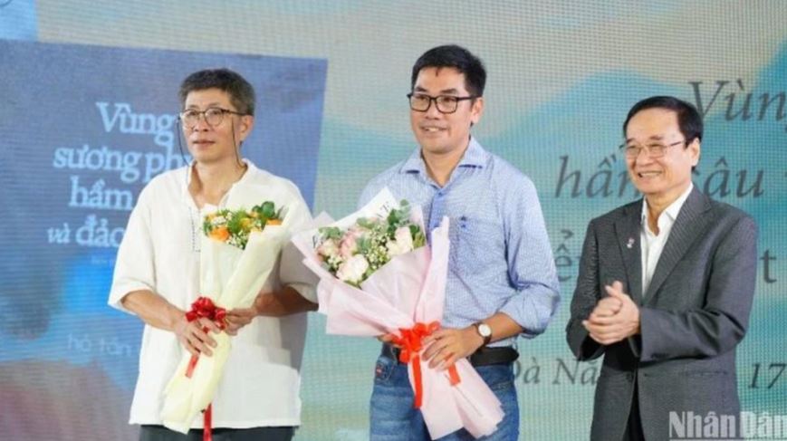 Ông Lương Minh Sâm, Chủ tịch Hội đồng Trường đại học Đông Á tặng hoa chúc mừng hai tác giả Trần Tuấn và Hồ Tấn Vũ. 