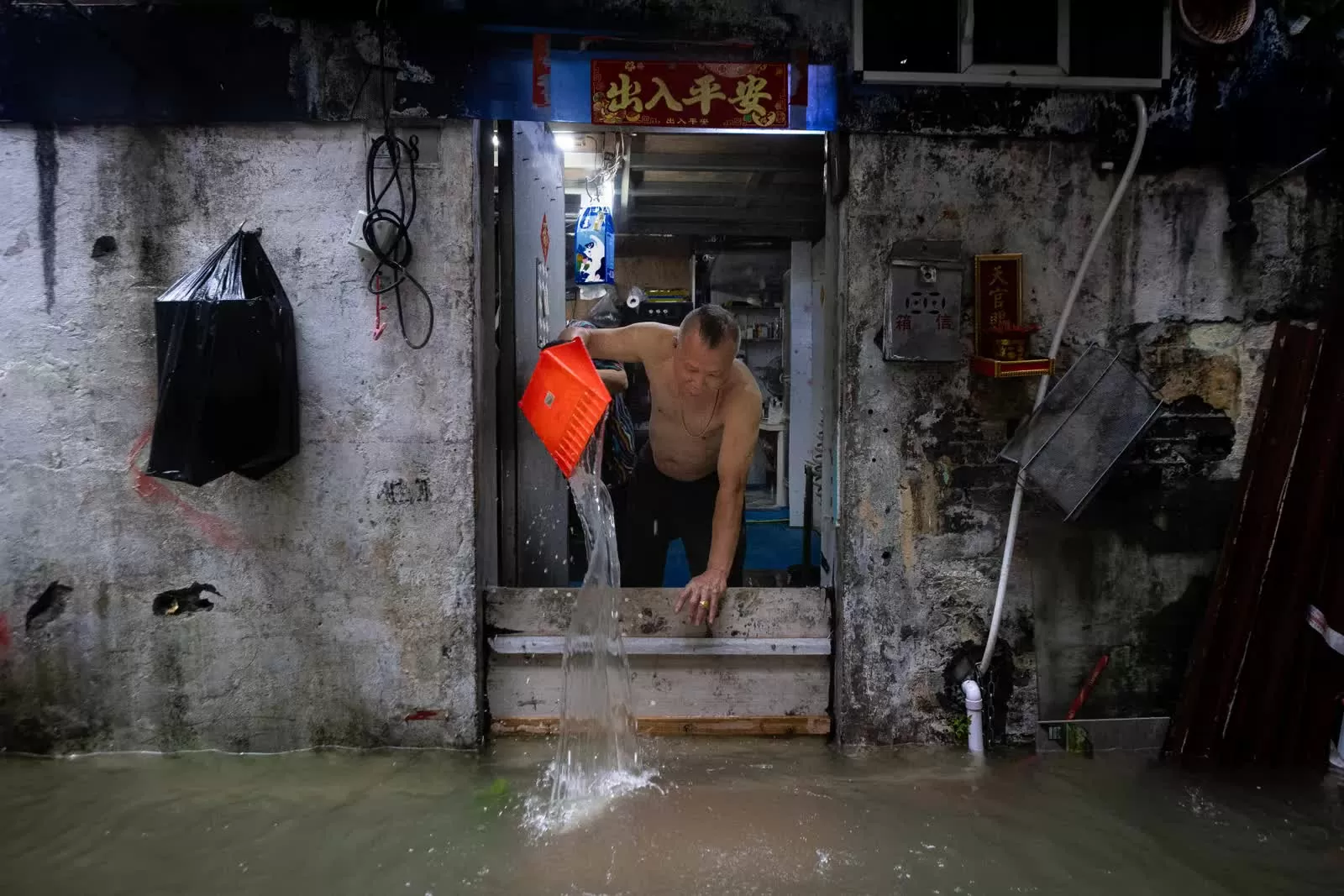 Một người đàn ông tát nước khỏi ngôi nhà ngập lụt của mình khi siêu bão Ragasa đi qua Ma Cao (Trung Quốc), ngày 24/9/2025. (Nguồn: CNA)