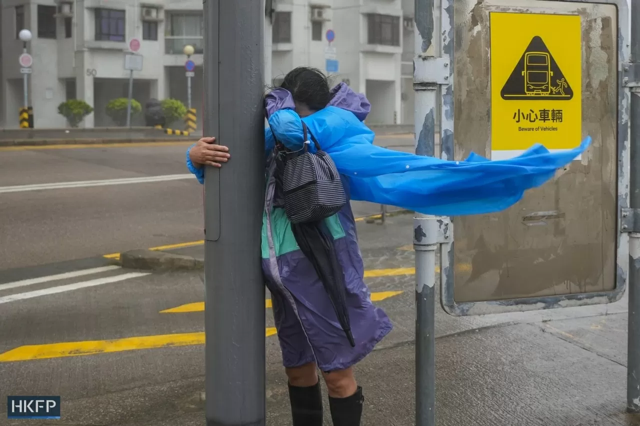 Từ rạng sáng, Đài quan sát Hong Kong (Trung Quốc) liên tiếp nâng mức cảnh báo bão, lên tới cấp số 10 (mức cao nhất) lúc 2h40, trước khi hạ xuống cấp 8 vào đầu giờ chiều. Đây là lần đầu tiên từ năm 1964, thành phố phải ban hành hai cảnh báo số 10 trong cùng một năm. Trong ảnh: Một phụ nữ bám vào biển báo giao thông để giữ thăng bằng trước sức gió mạnh của siêu bão Ragasa ở Hong Kong, Trung Quốc. (Nguồn: HKFP)