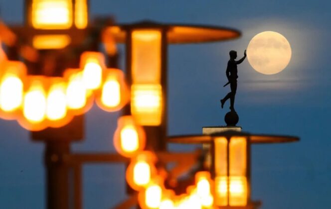 Nhiếp ảnh gia Julian Stratenschulte bố tr&iacute; g&oacute;c chụp ho&agrave;n hảo để Mặt Trăng nằm cạnh tượng Torchbearer.