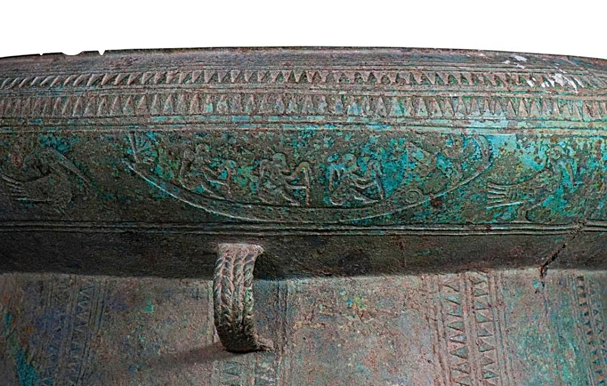 Tang trống có 3 băng hoa văn, chia làm hai phần trên dưới. Phần trên là 2 băng răng cưa ngược chiều nhau, ngăn cách bởi một đường chỉ nổi. Phần dưới là băng hoa văn chủ đạo, trang trí hình thuyền và chim xen kẽ. Có bốn chiếc thuyền bơi theo hướng ngược chiều kim đồng hồ, thân thuyền cong, có những chấm nổi nhỏ. Đuôi thuyền xòe ra hình nan quạt. (Ảnh: Bảo tàng Nghệ An cung cấp).